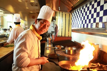 chef working on grill, smiling at camera