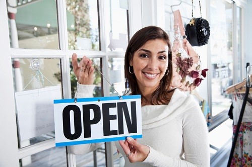 retail working holding up an open sign