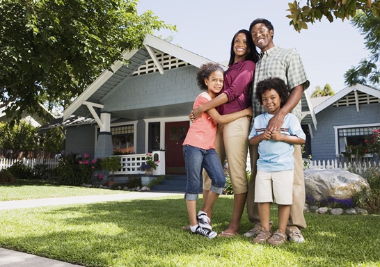 family posing in front of house