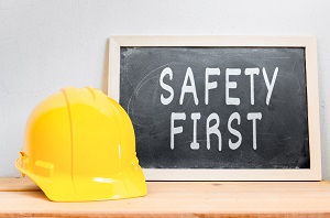 safety first written on a chalkboard next to a yellow hard hat